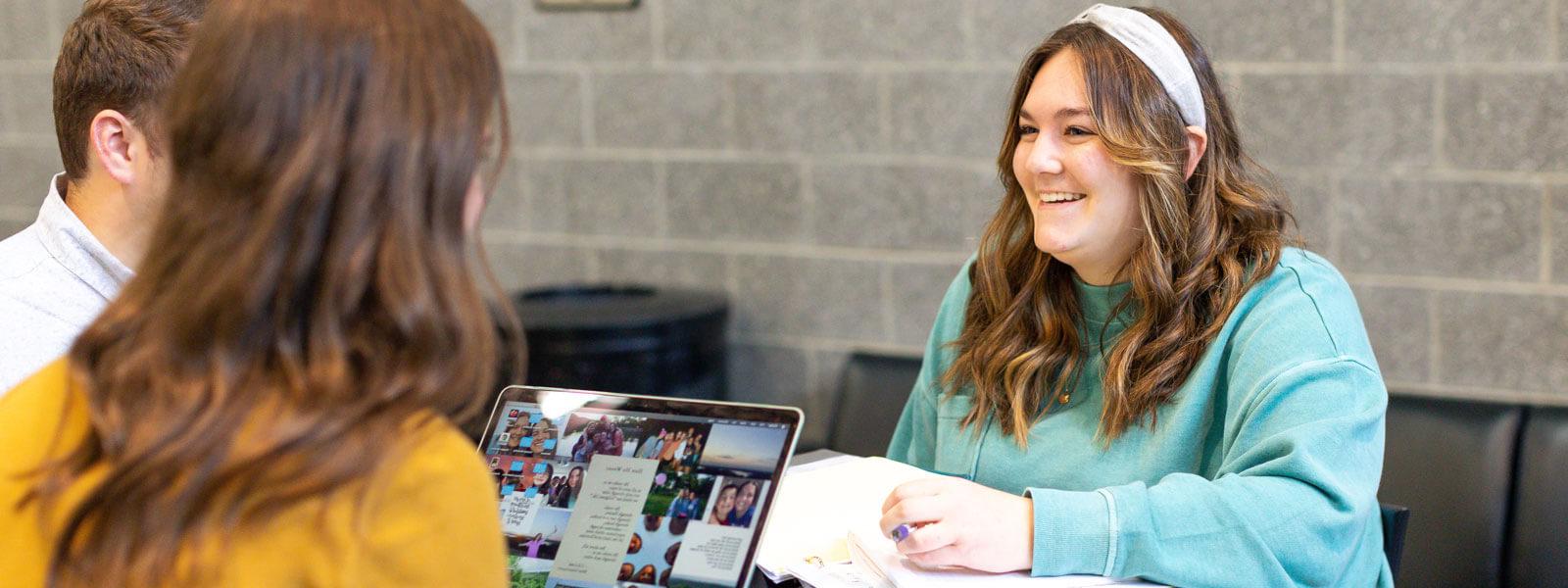 professor chats with students at table in Sports Cafe