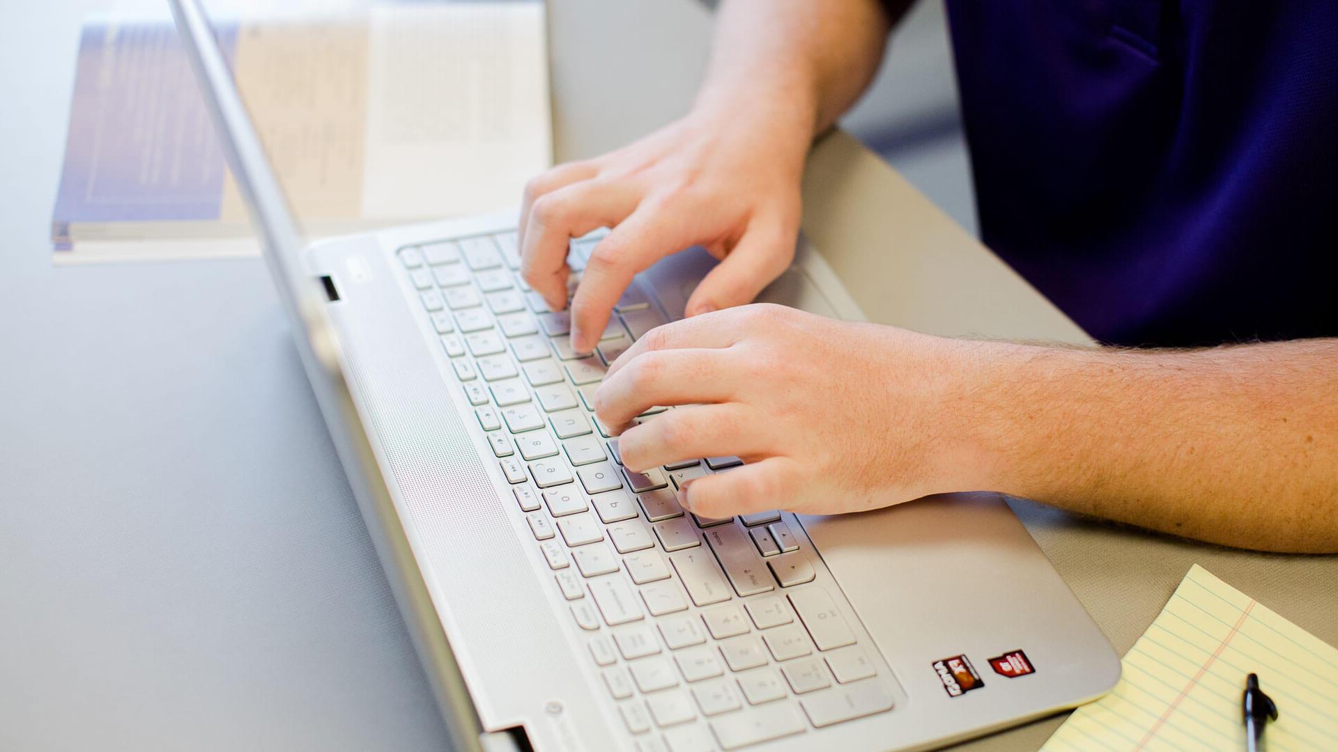 a close up view of hands typing on a keyboard